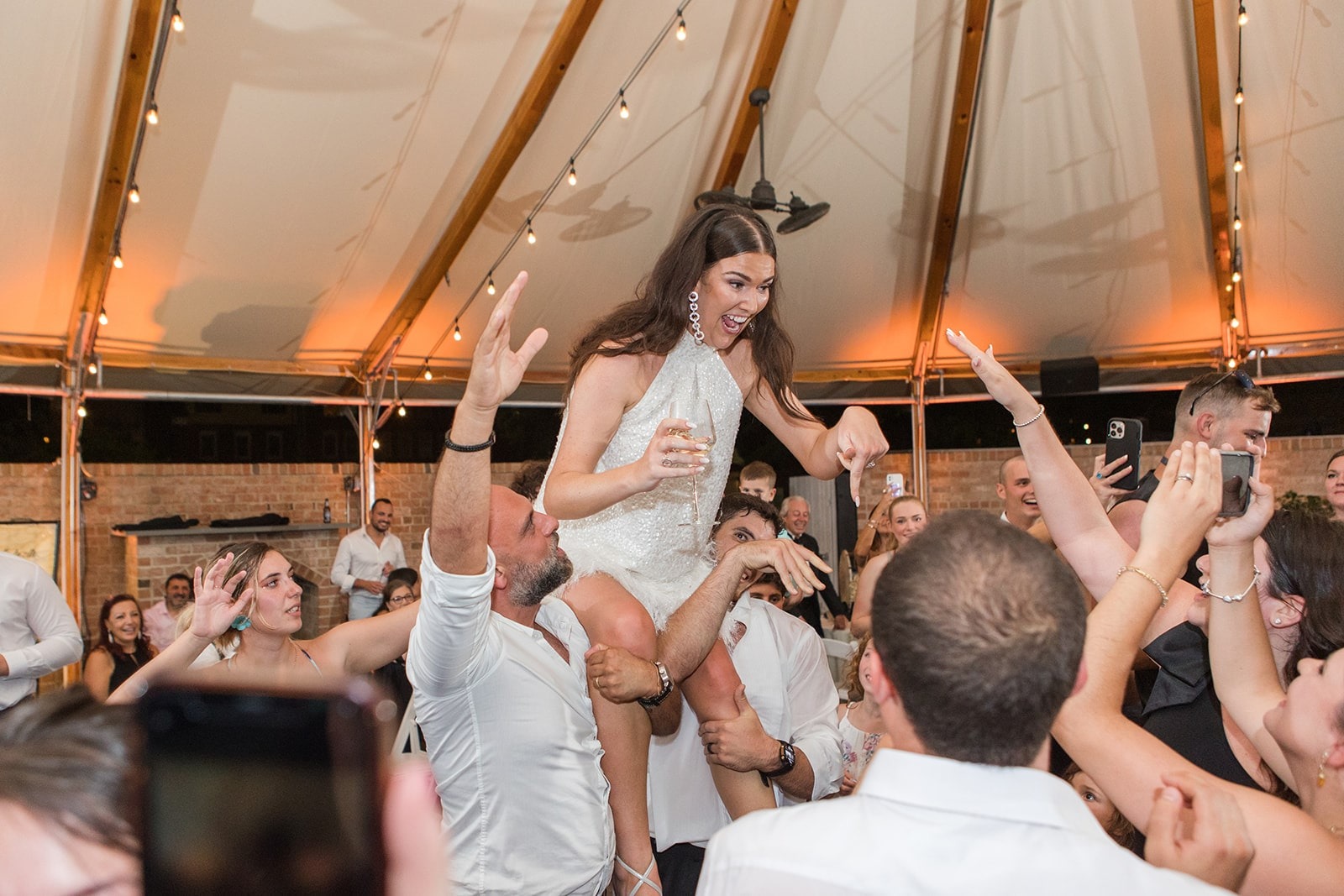 bride up on two guys shoulders at wedding