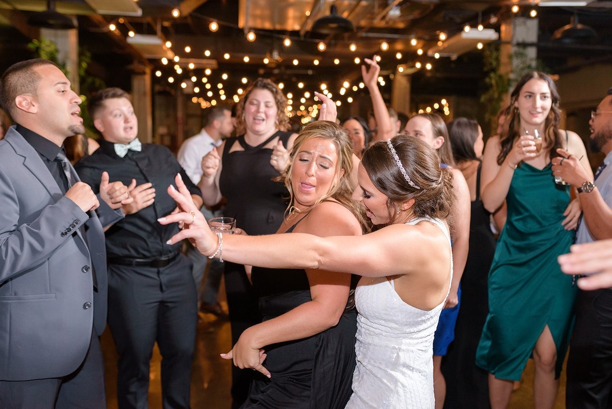 bride dancing up against bridesmaid in black dress