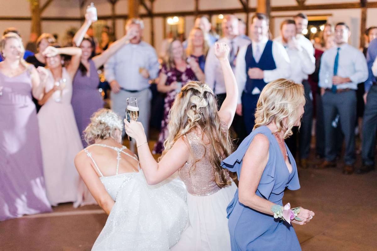 bride bent over dancing with two women at wedding 