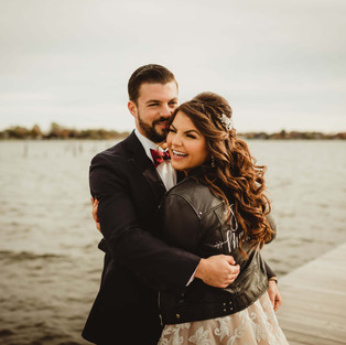 bride and groom pose by the water