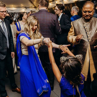 woman in blue and gold sari dancing with young girl in matching sari