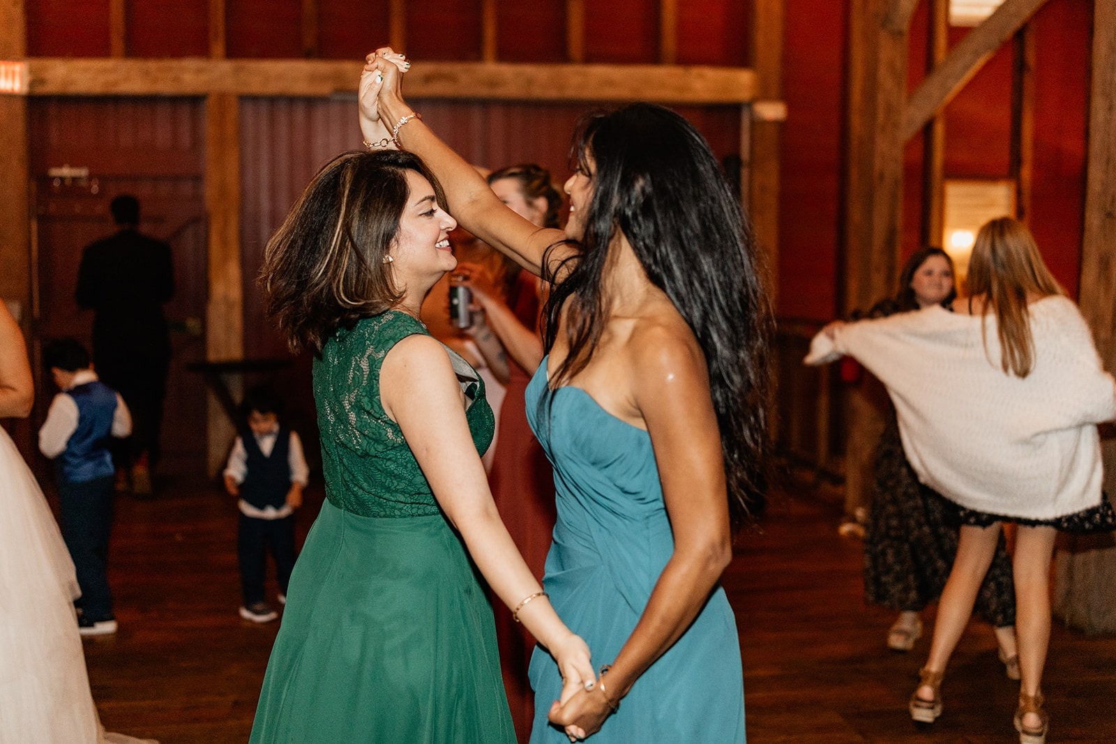 two women dancing in green and teal dresses dancing at wedding