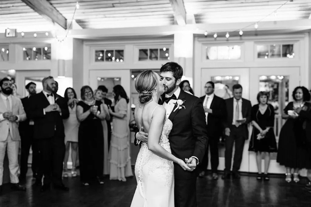 bride and groom kiss during first dance while guests watch