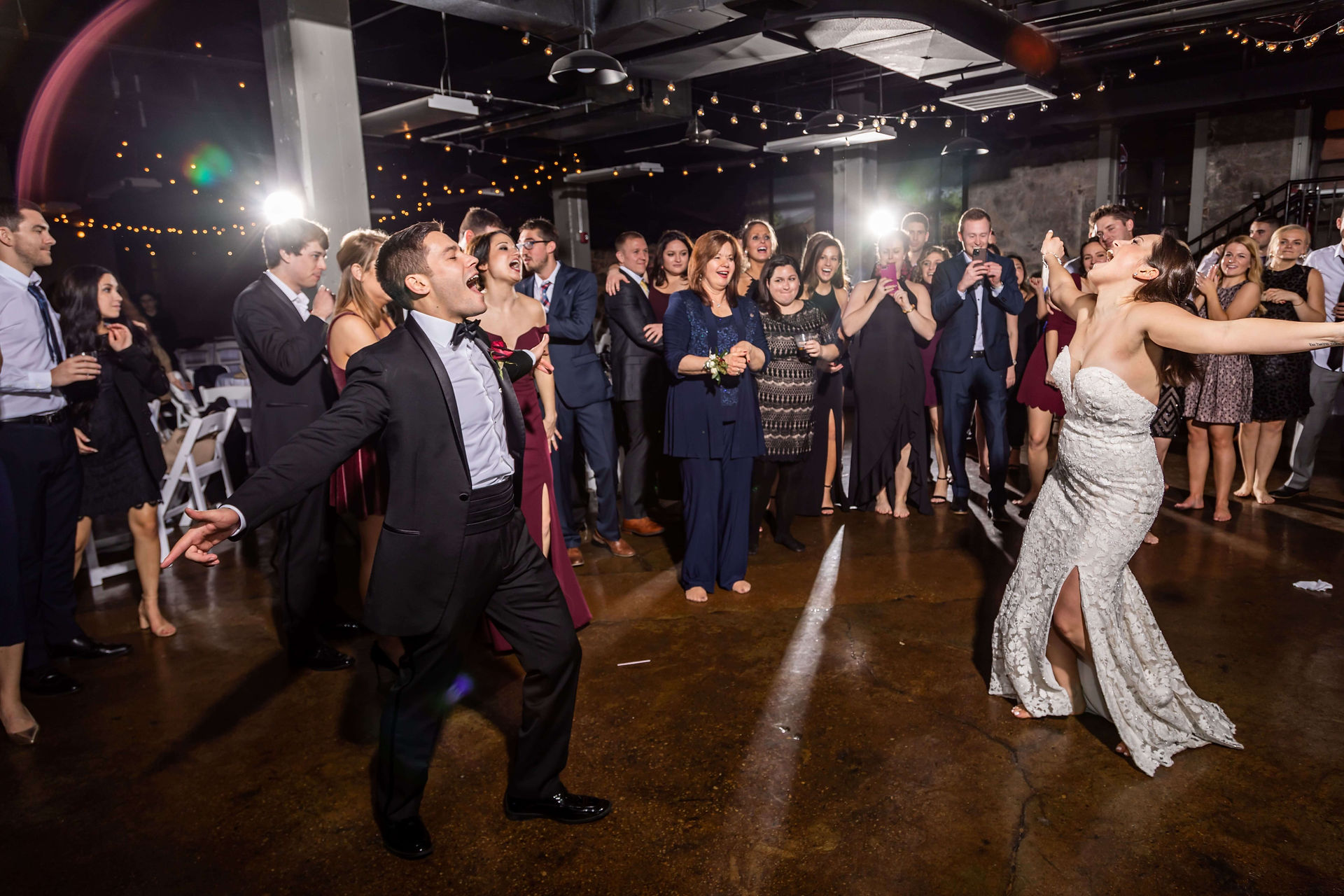 bride and groom sing and dance surrounded by wedding guests