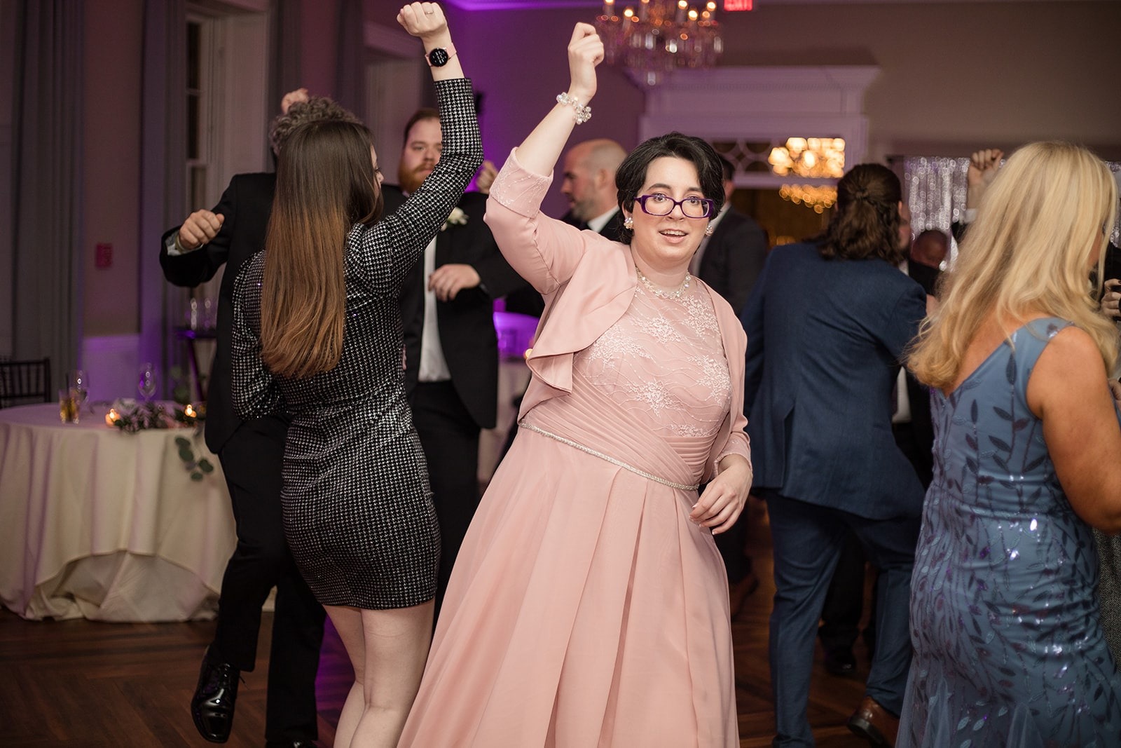 woman in pink dress dancing with hand up at wedding
