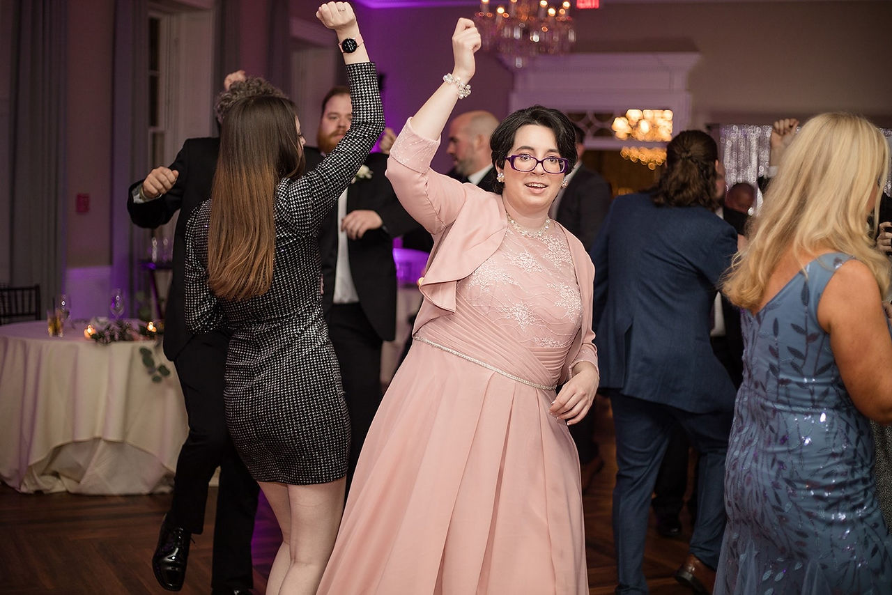 woman in pink dress dancing with hand up at wedding