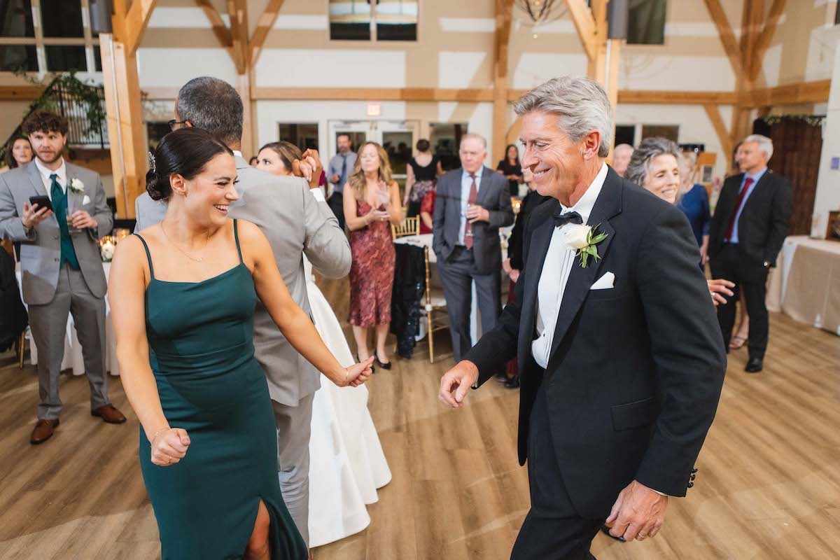 woman in dark green dress and older man in tux dancing at wedding
