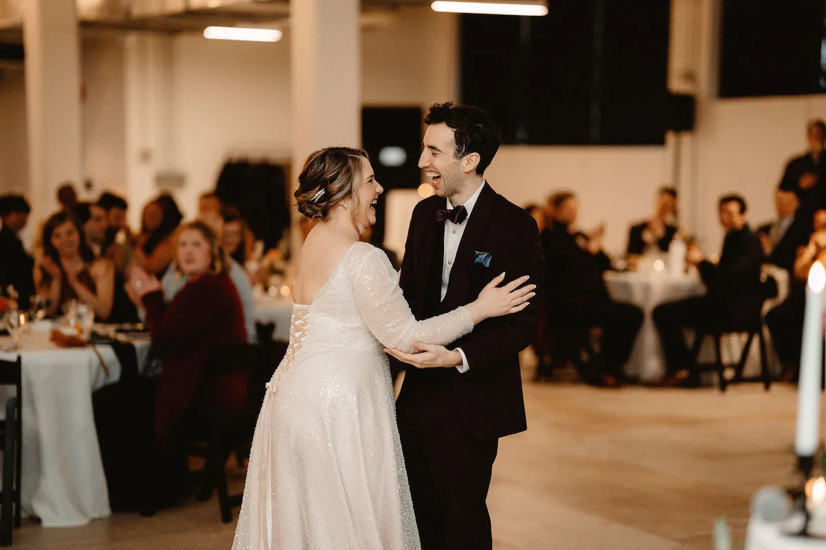 bride and groom laughing and dancing while guests watch