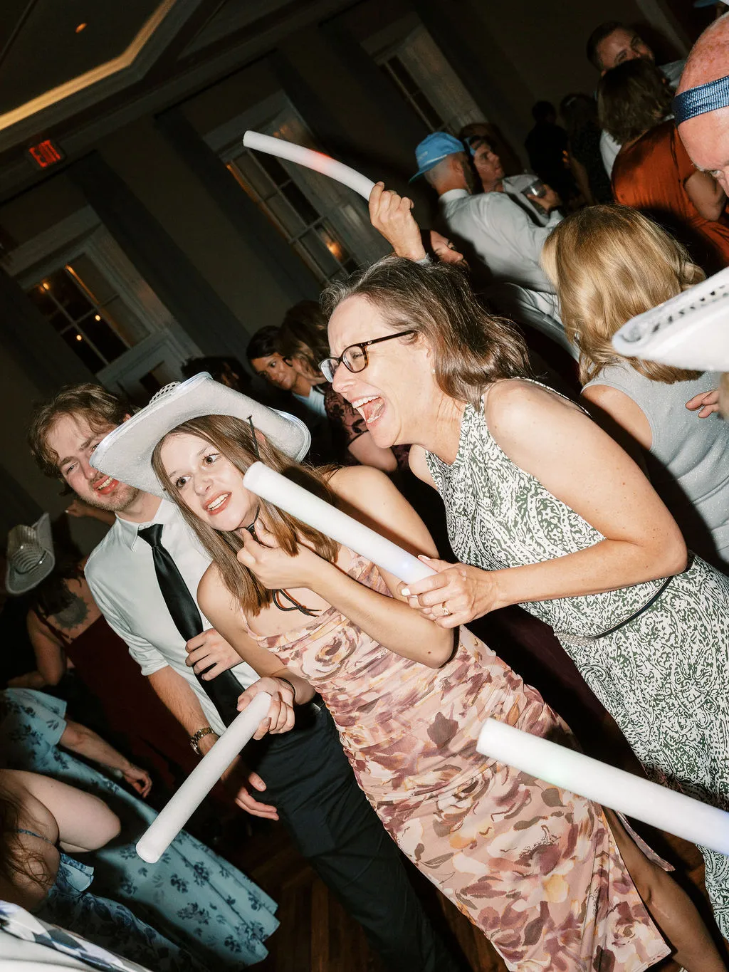 women dancing at wedding, holding glow sticks