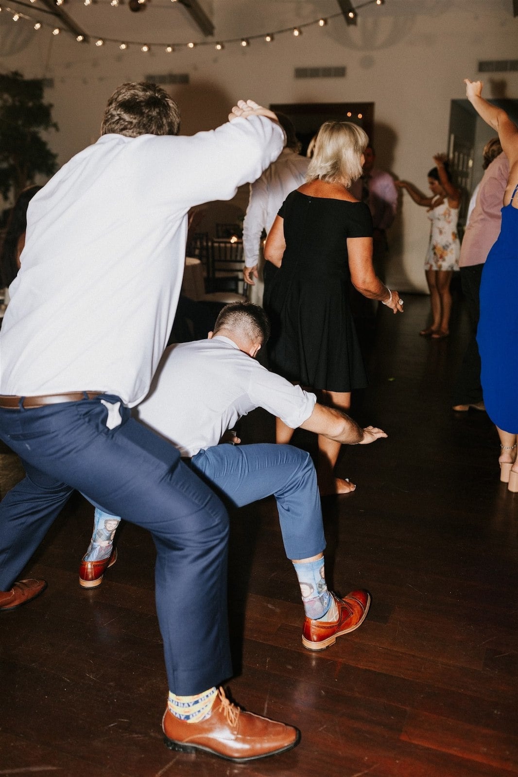 guy gets low dancing in front of other guy at wedding