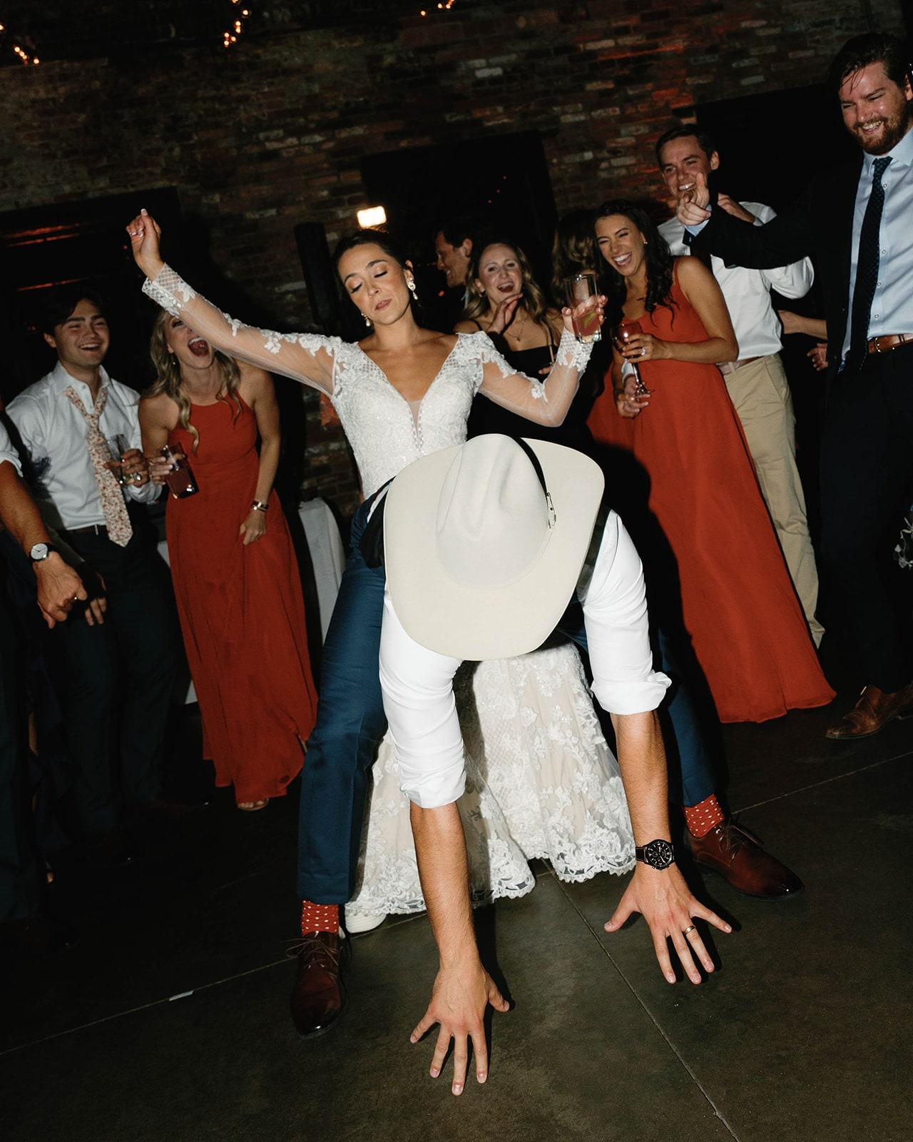 groom in cowboy hat bent over dancing in front of bride