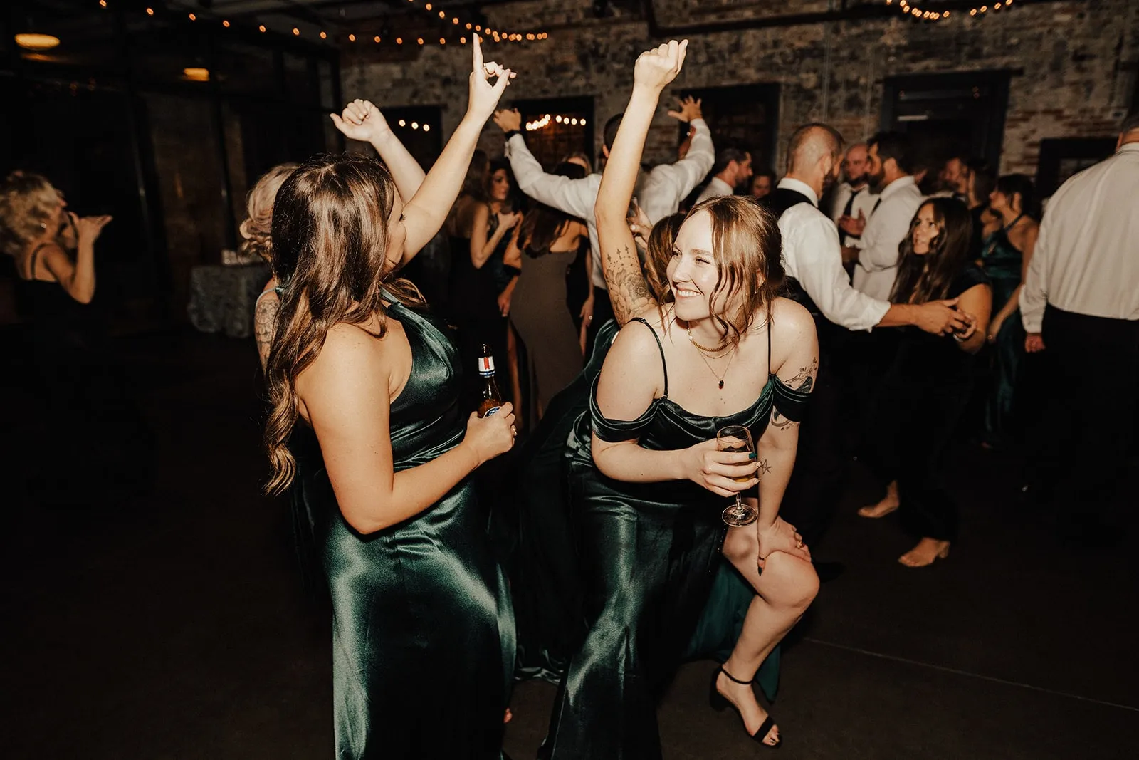 bridesmaids in dark green dresses dancing at wedding