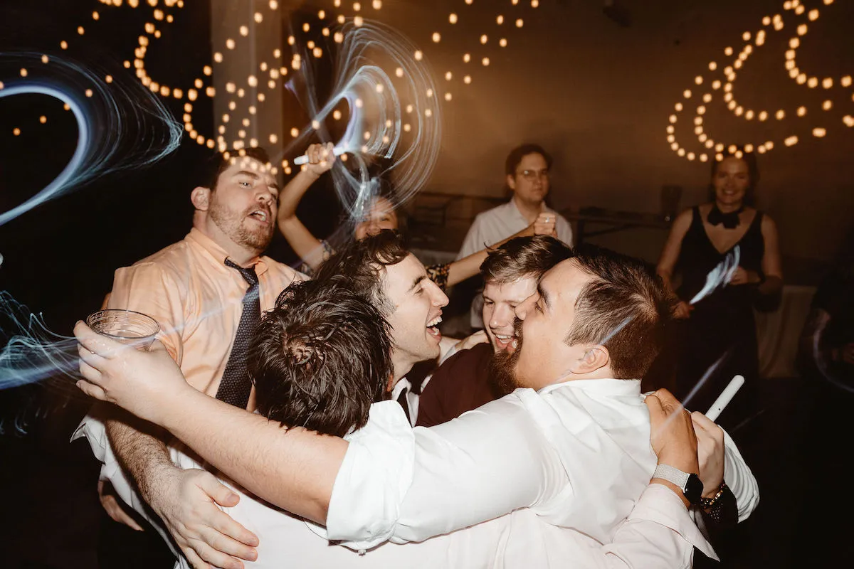 five guys hugging and dancing at wedding