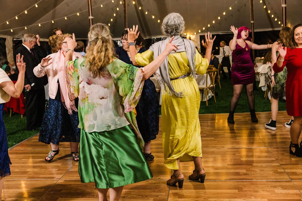 women dancing with hands up in a tent wedding