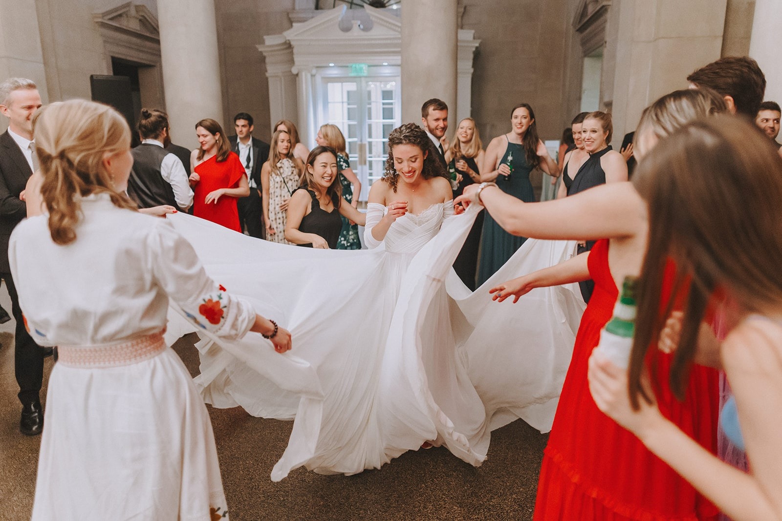 women spreading out brides dress while she dances