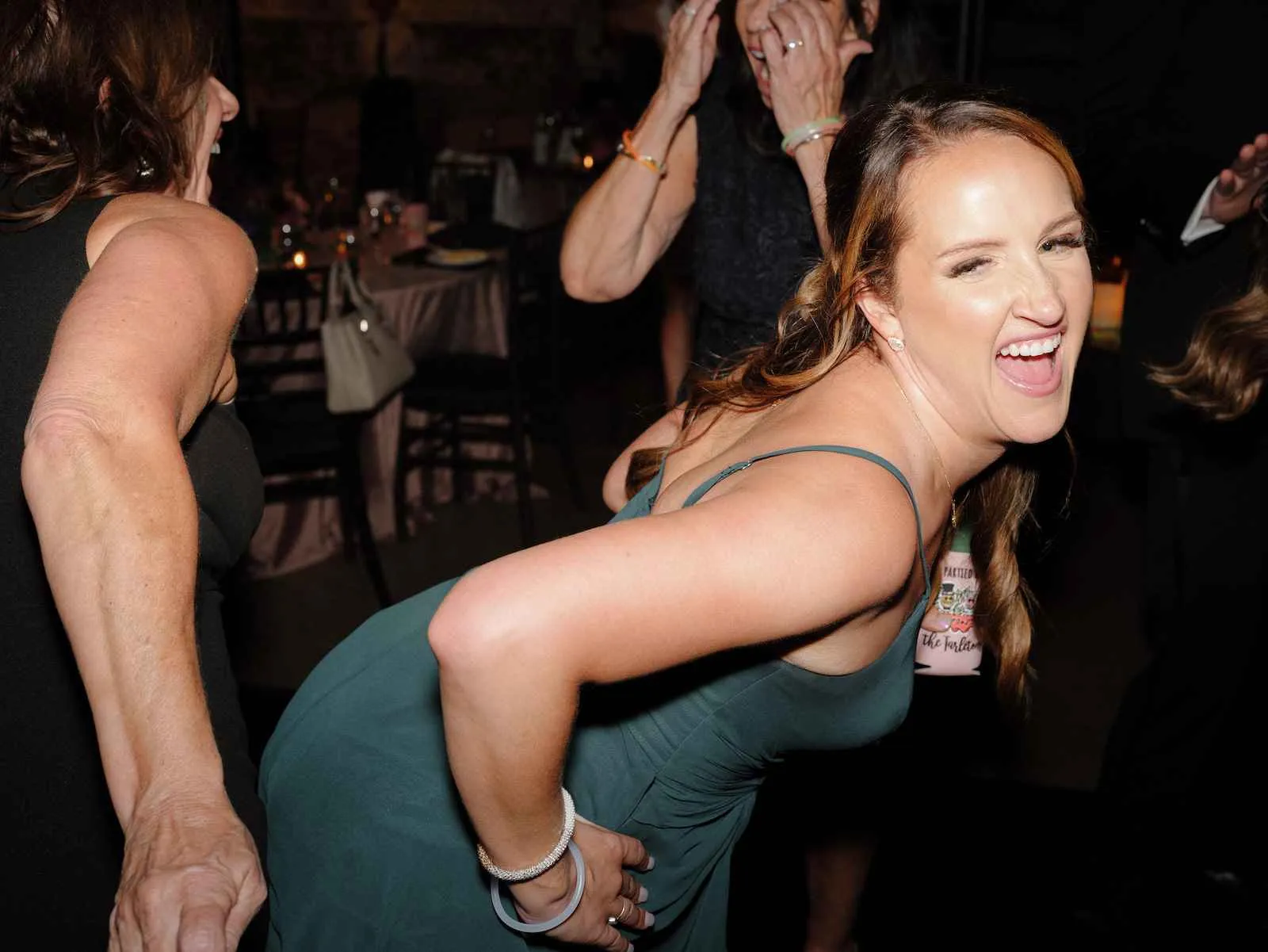 bridesmaid in dark green dress dancing at wedding