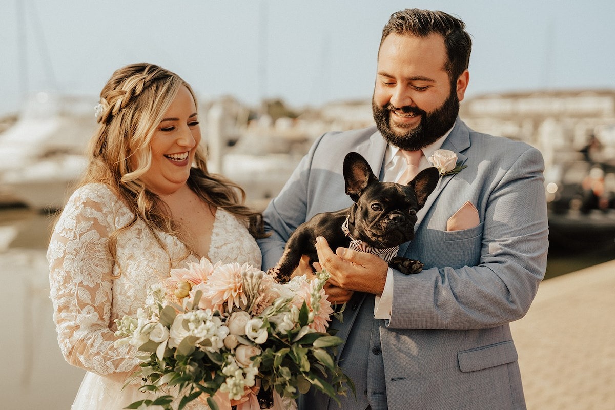 bride and groom pose with their small dog