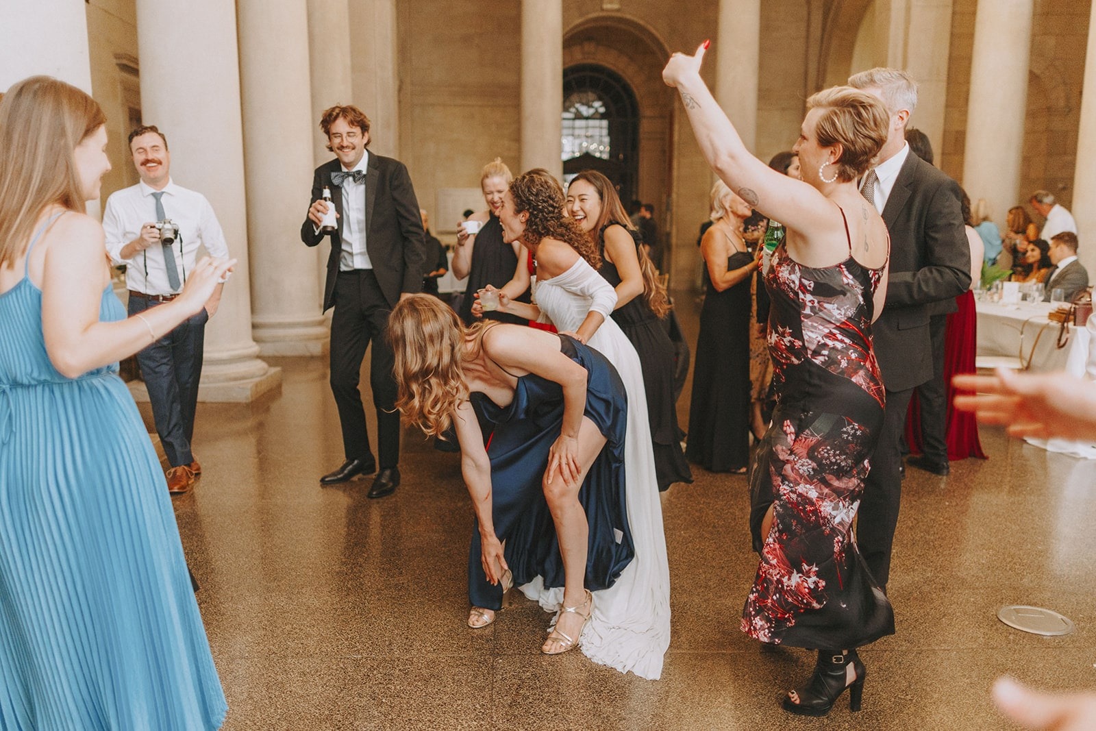 woman in navy dress dancing bent over in front of bride