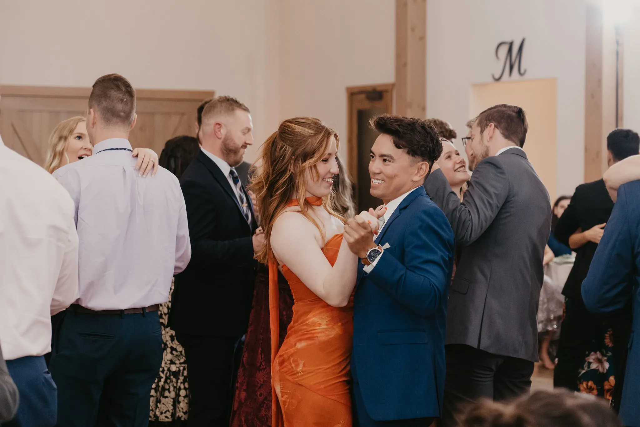 woman in organge dress dancing with man in navy suit