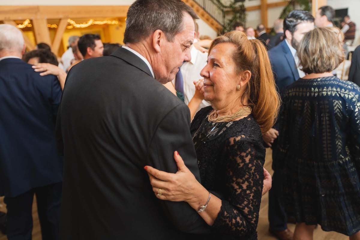 older couple dressed in black dancing at wedding