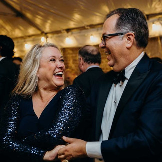 older smiling woman being spun by man dancing at wedding