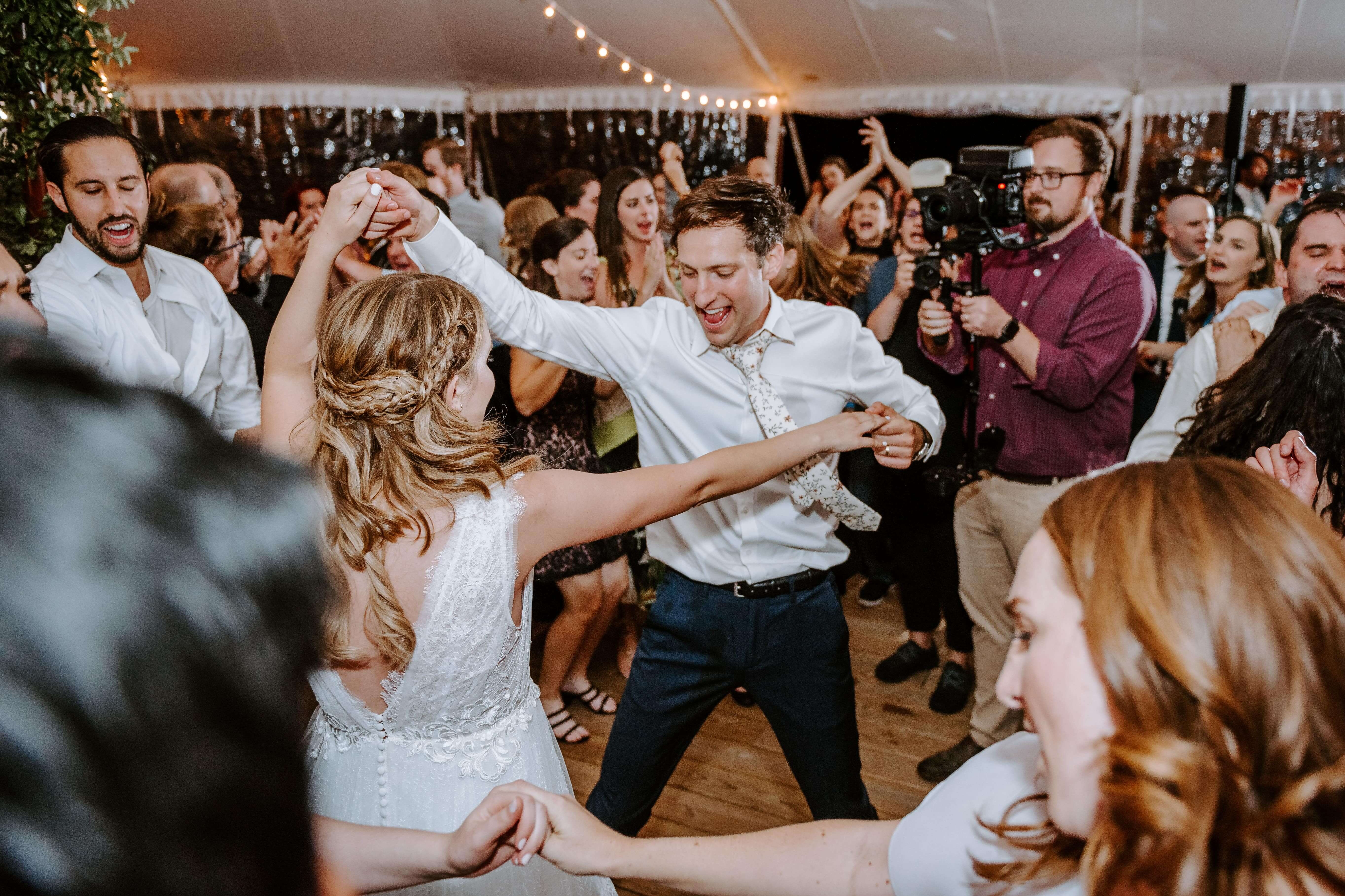 bride and groom dance vibrantly while guests surround them