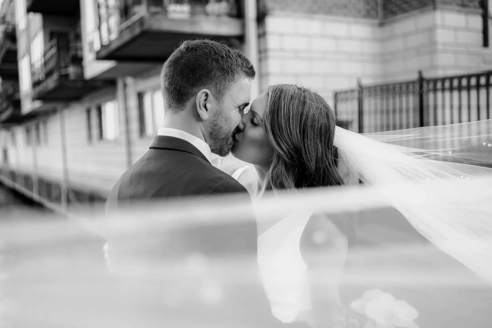 bride and groom kiss while veil obscures a bit of the image