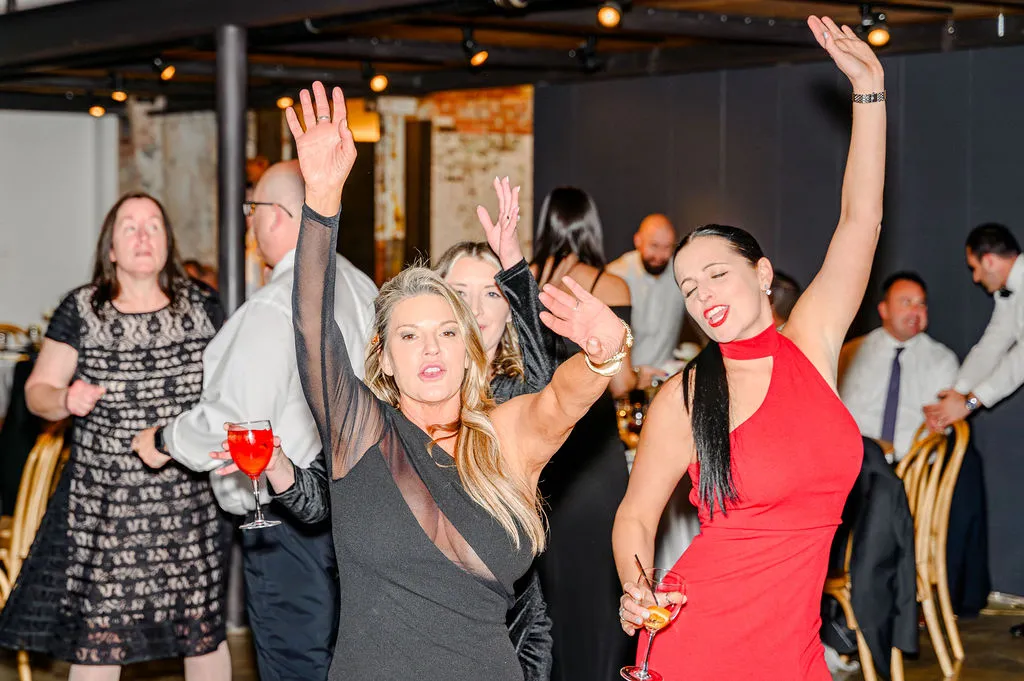 two women dancing with hands up at wedding