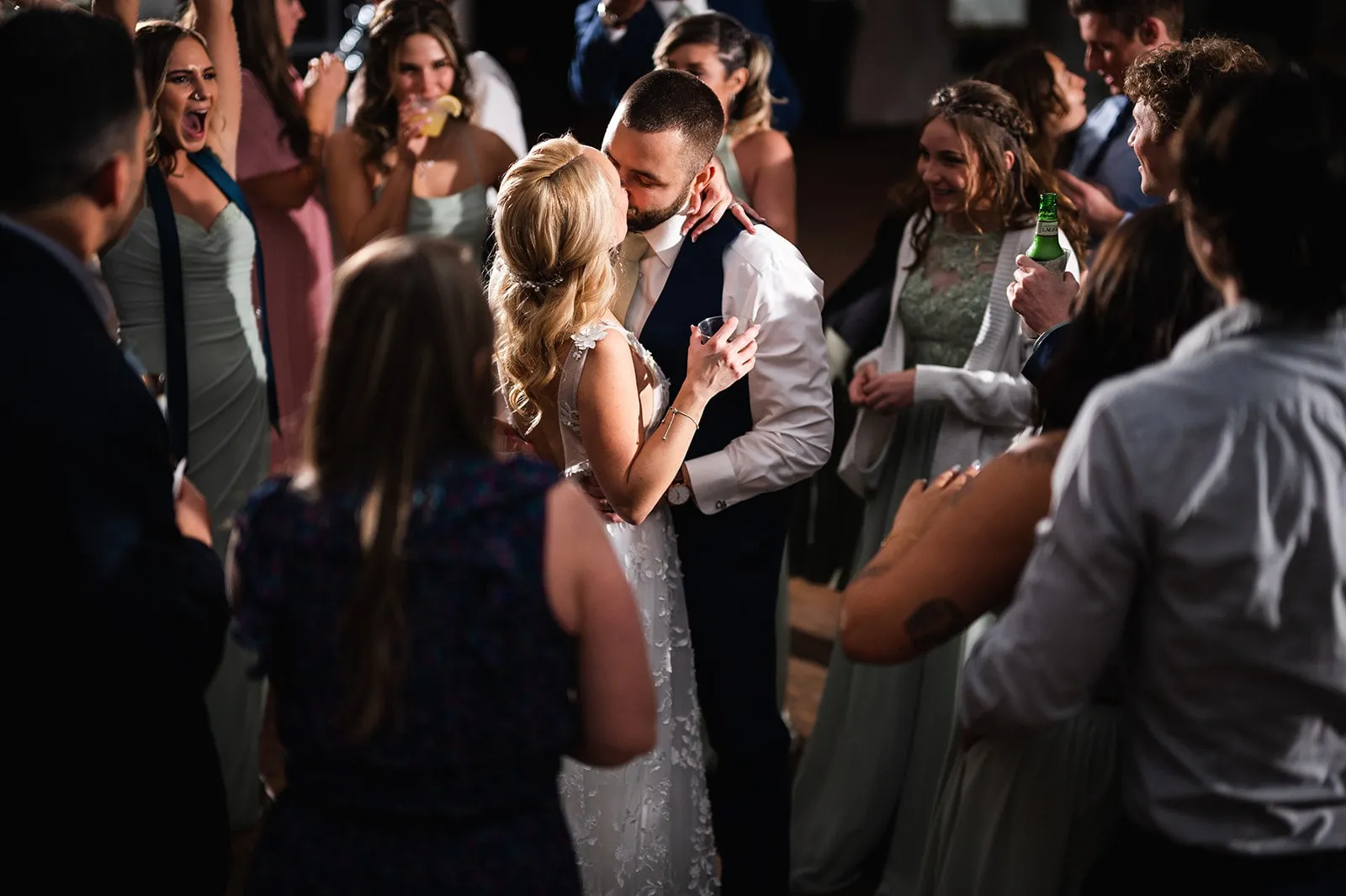 bride and groom dancing and kiss while surrounded by wedding guests