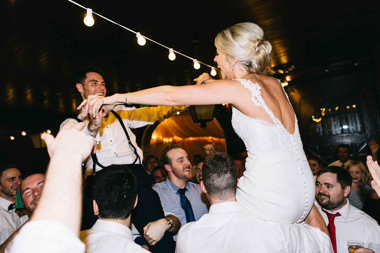 bride and groom up on shoulders of guests at wedding