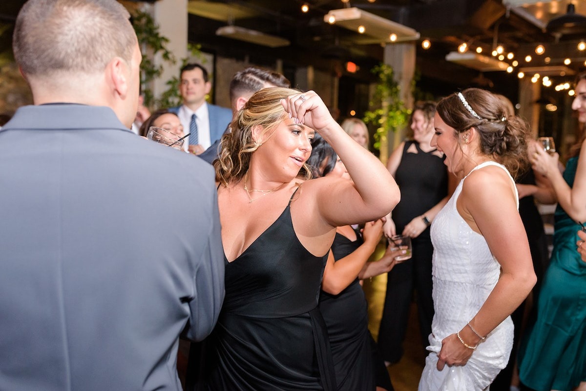 bridesmaid in black dress dancing among guests