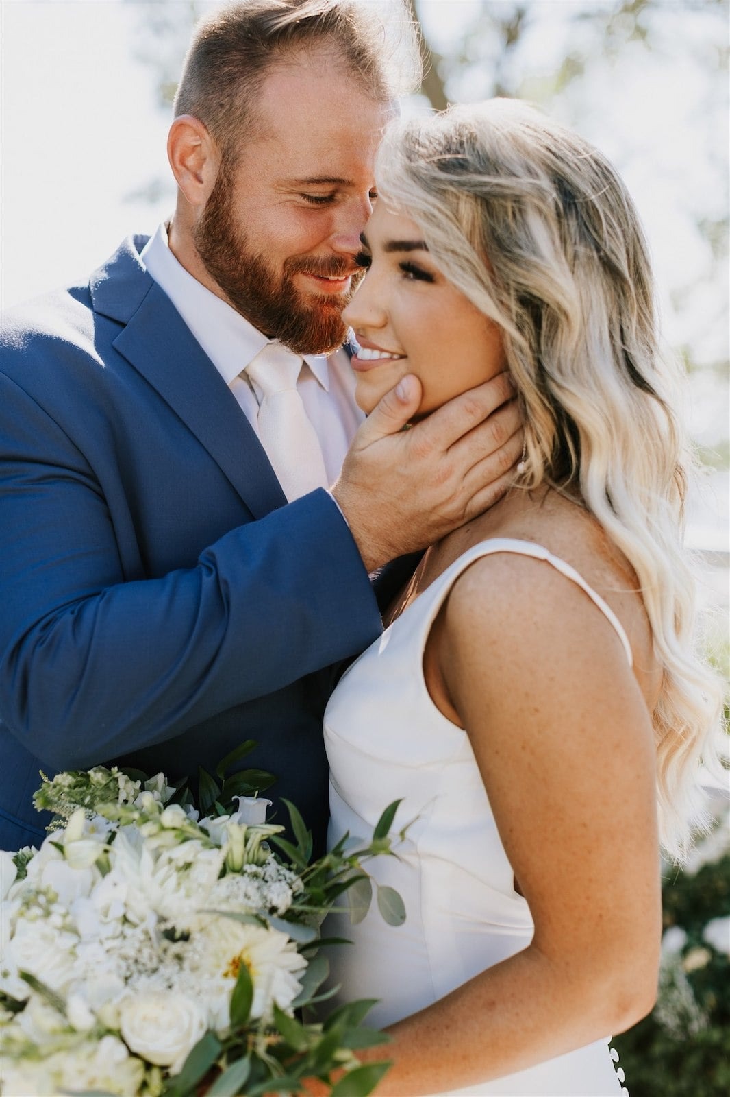 bride and groom posing with groom's hand on bride's cheek