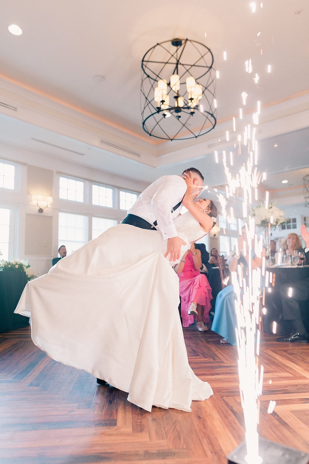 groom dips and kisses bride while cold sparks go off