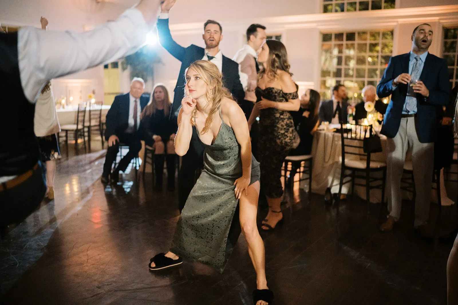 woman in dark green dress dancing in front of boyfriend at wedding