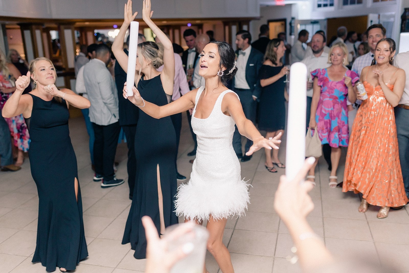 bride in short white dress dancing with friends
