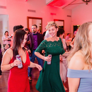woman in green dress dancing and looking at woman in red dress at wedding