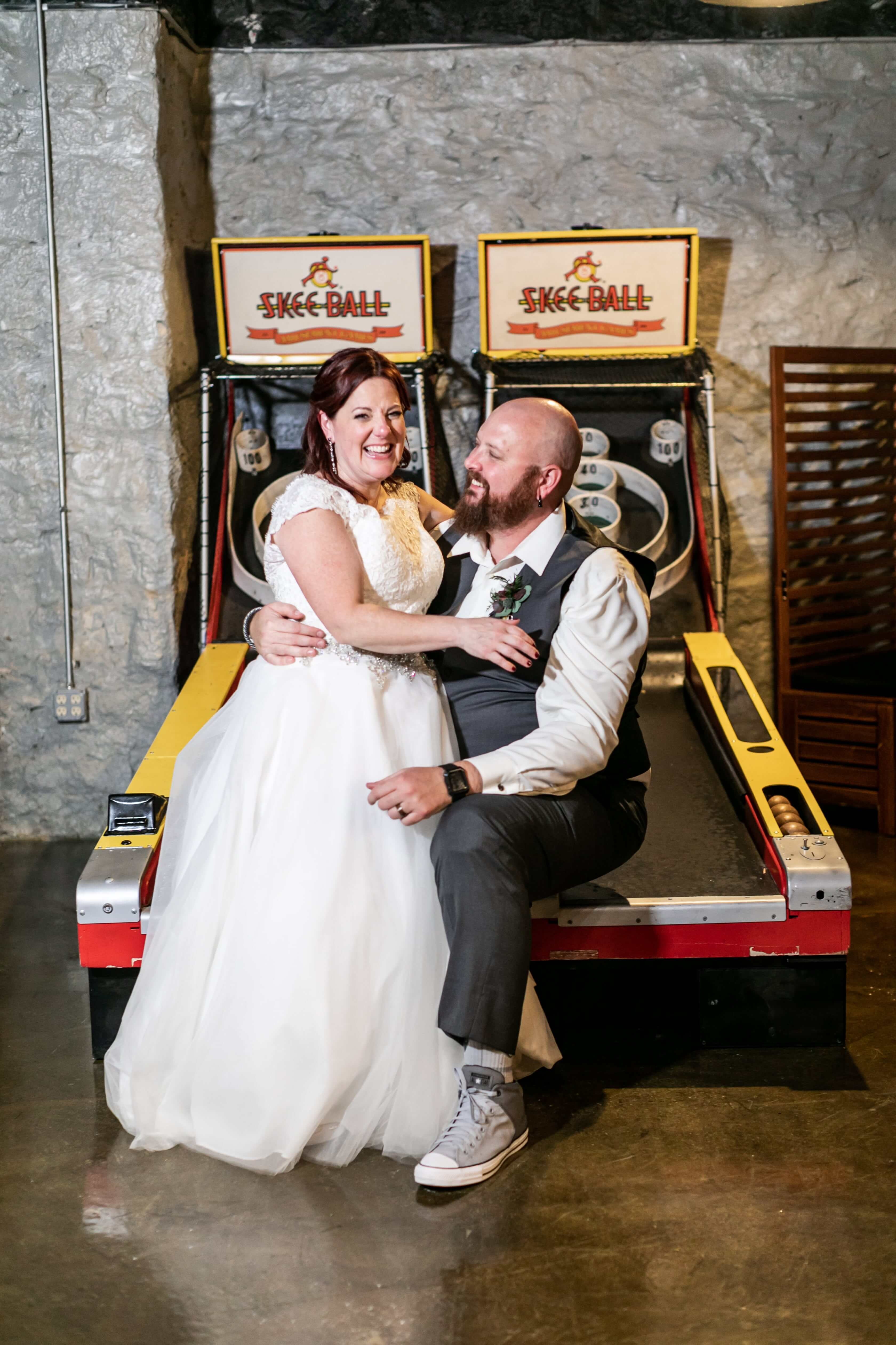 bride and groom pose while seated on arcade game