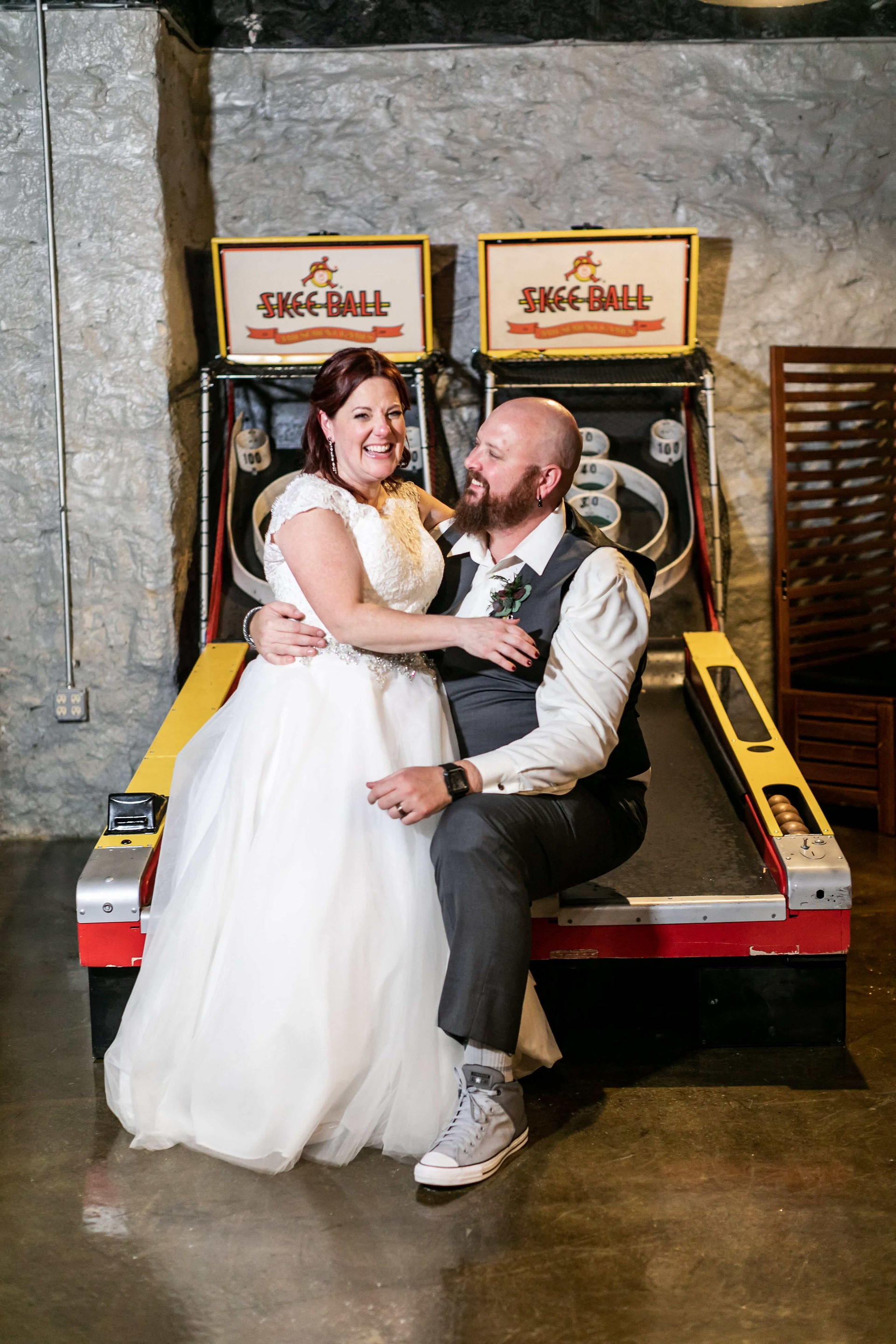 bride and groom pose while seated on arcade game