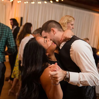 young couple slow dancing at wedding while woman in smiling