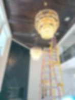 Large tiered crystal chandeliers and ladder in a foyer