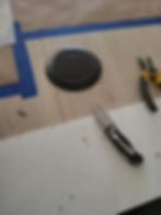 Round black floor outlet installation with tools on wood.