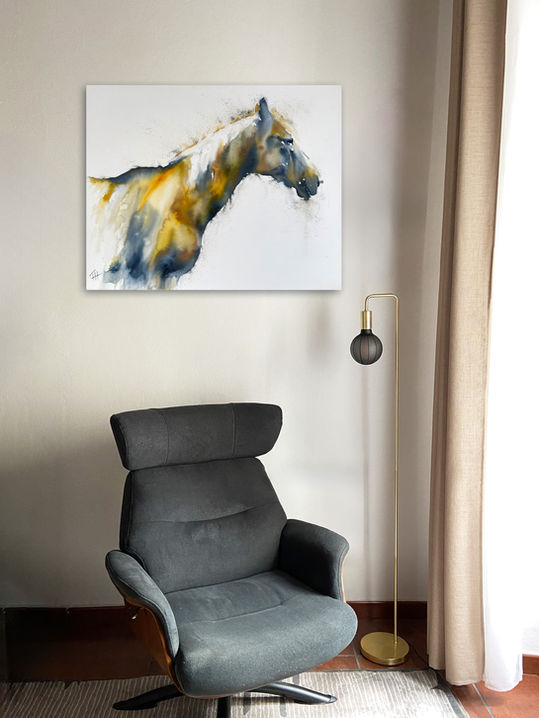 Original painting Presence displayed on a light wall above a grey reading chair beside a floor lamp.