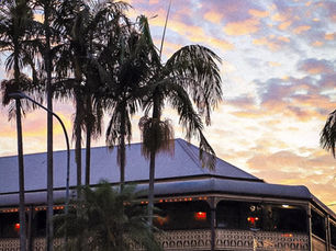 Sunset and palm trees with heritage Queenslander building