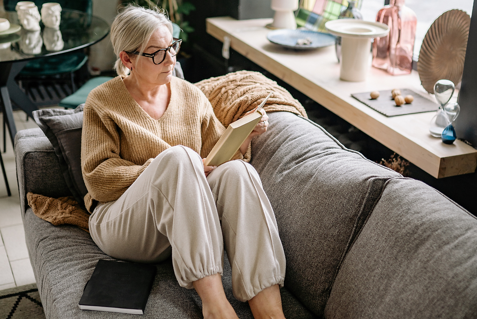 Woman wearing casual clothes and glasses, sitting on a  sofa reading a book, searching for answers to her chronic fatigue