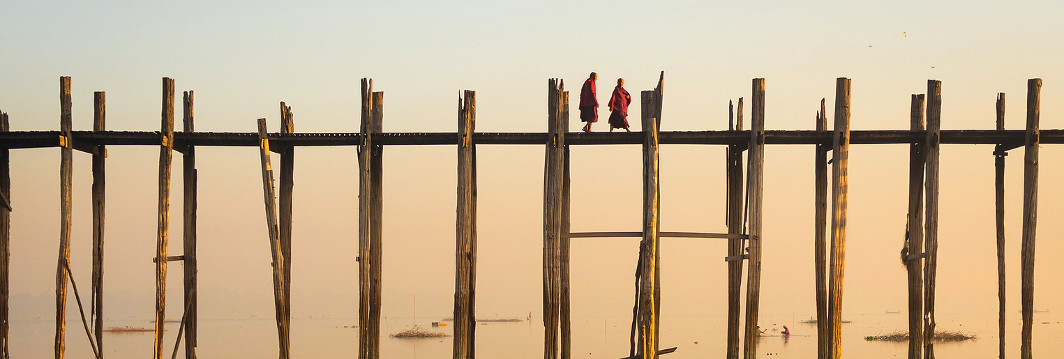 Reflection of Monks Crossing a Wooden Bridge