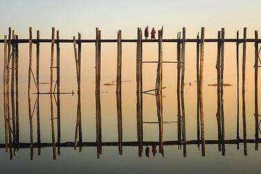 Reflection of Monks Crossing a Wooden Bridge