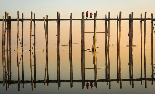 Reflection of Monks Crossing a Wooden Br