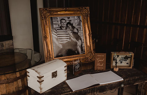 Monochrome picture in a gold frame, a chest and guest book on table.