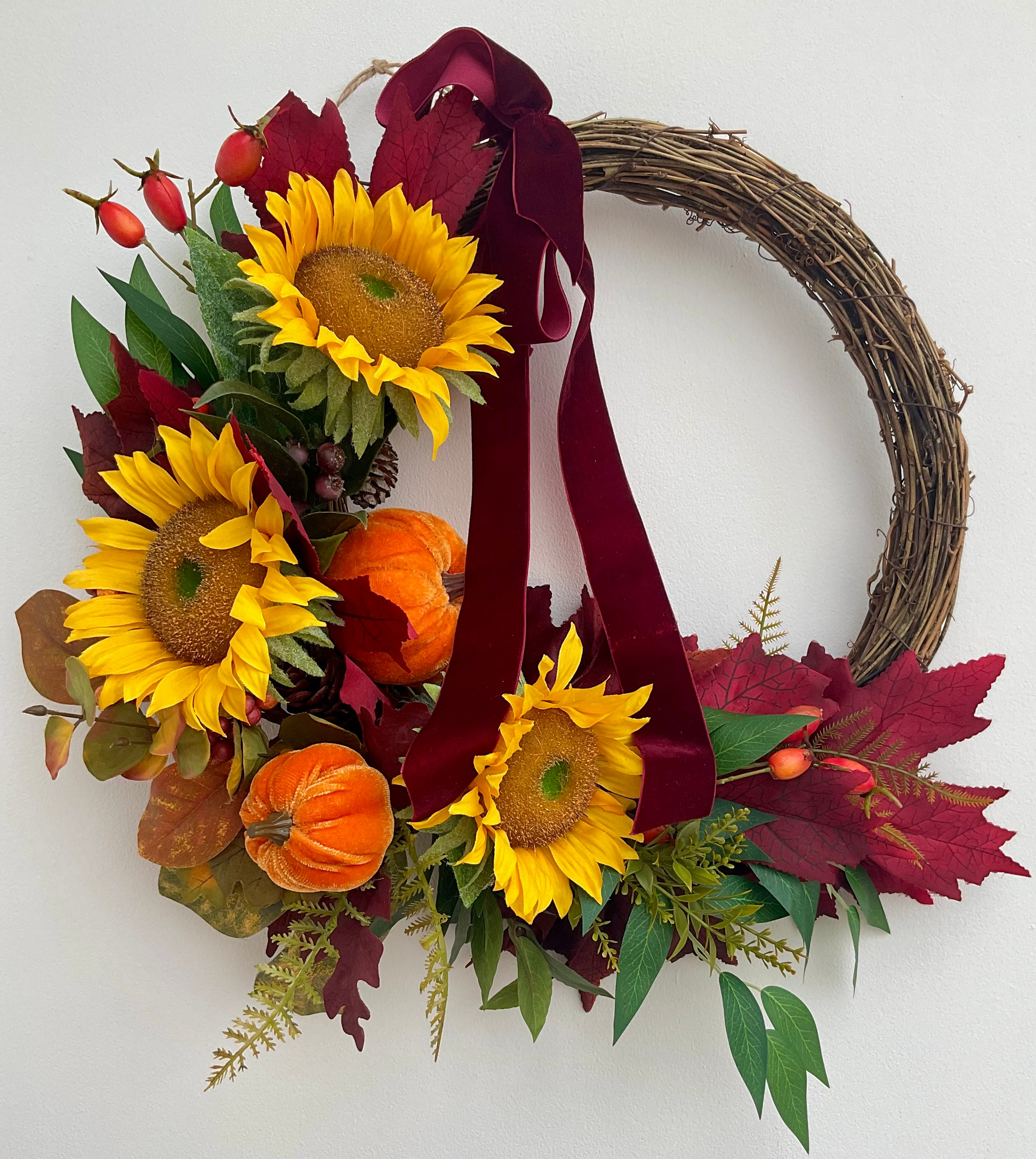 Front Spiced Autumn Bloom wreath with faux sunflowers, berries, leaves, ferns, velvet pumpkins, and dark red ribbon.