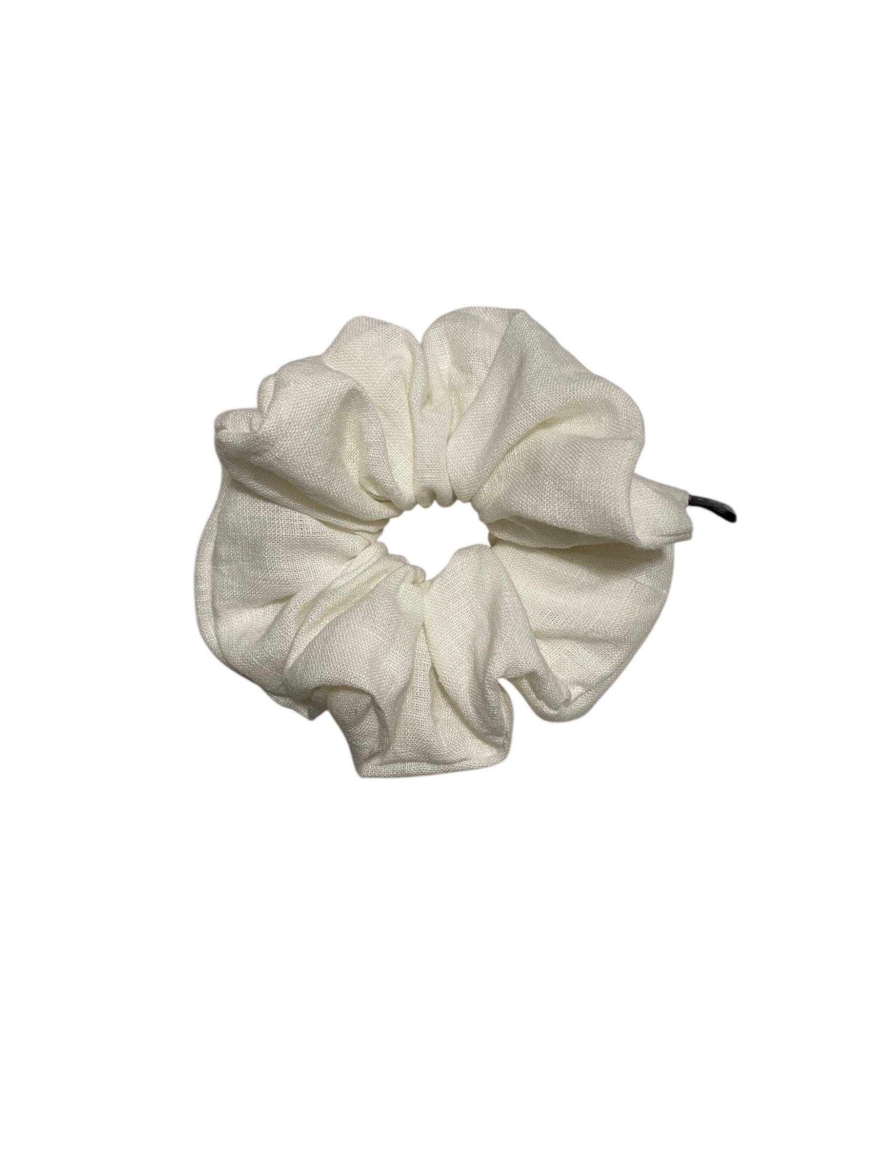 Close-up of a white linen scrunchie, showcasing its soft, textured fabric. The minimalist design and crisp white color offer a simple, elegant accessory for tying back hair.